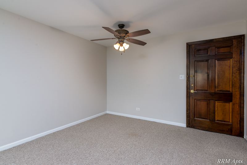 Dining area with beige carpet, ceiling fan and a dark wood entry door, Maple Avenue apartment 2C