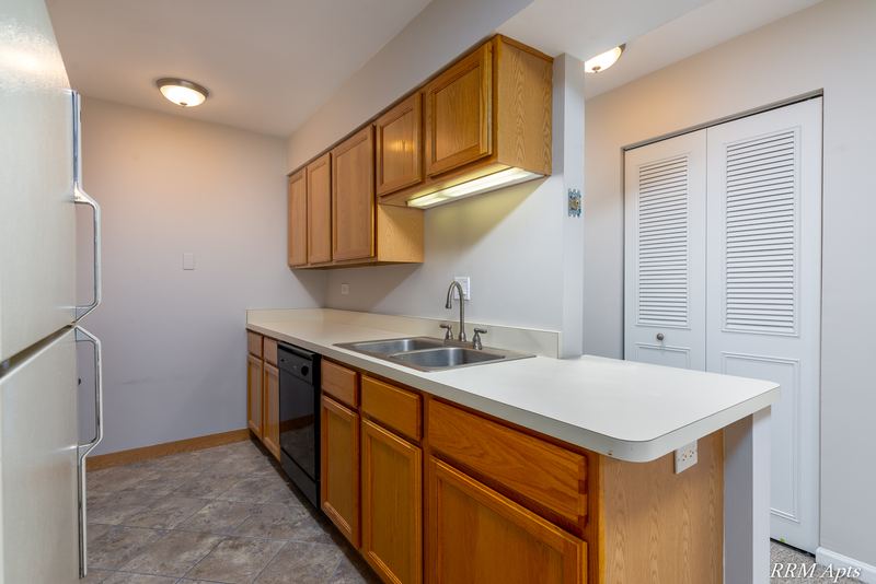 Kitchen with wood cabinets, white refrigerator, black dishwasher and a peninsula counter, Maple Avenue apartment 2C