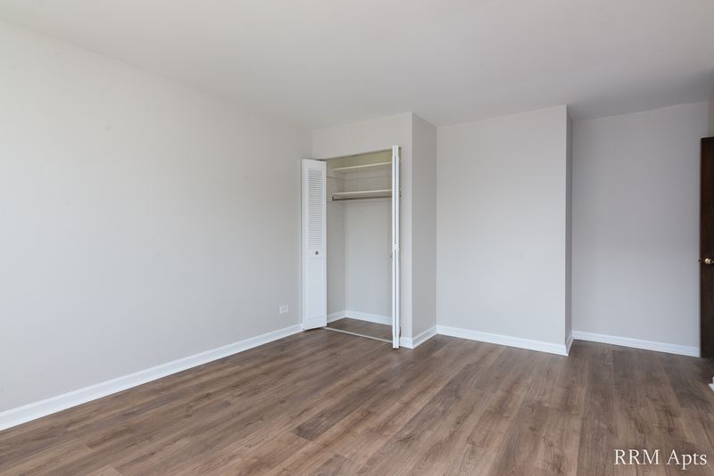 Bedroom with wood laminate floor, gray walls, an open closet with shelf and a doorway, Maple Avenue apartment 2F
