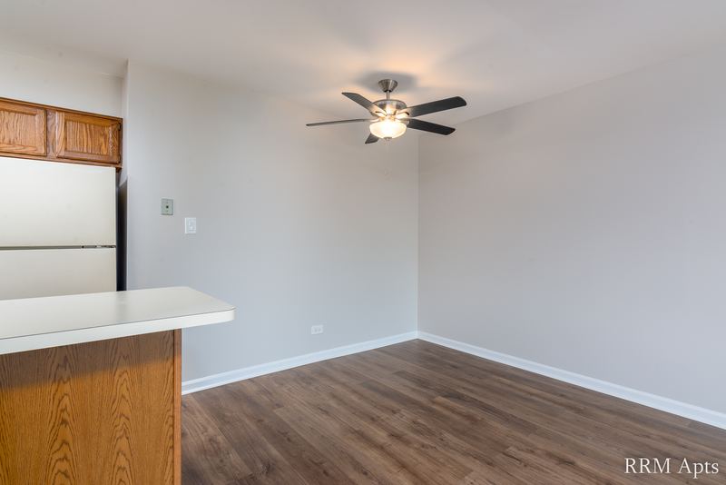 Dining area with wood laminate floor, ceiling fan and a kitchen peninsula with wood cabinet, Maple Avenue apartment 2F