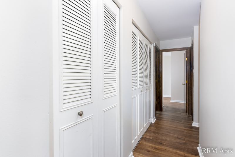 Hallway with white louvered closet doors, wood laminate floor and doorways to the bedrooms, Maple Avenue apartment 2F