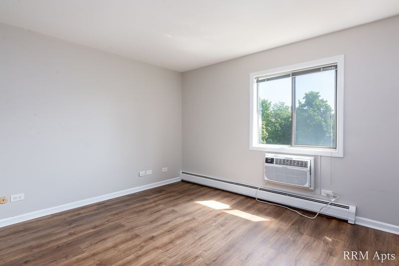 Bedroom with wood laminate floor, a window with wall air conditioner and baseboard heat, Maple Avenue apartment 2F