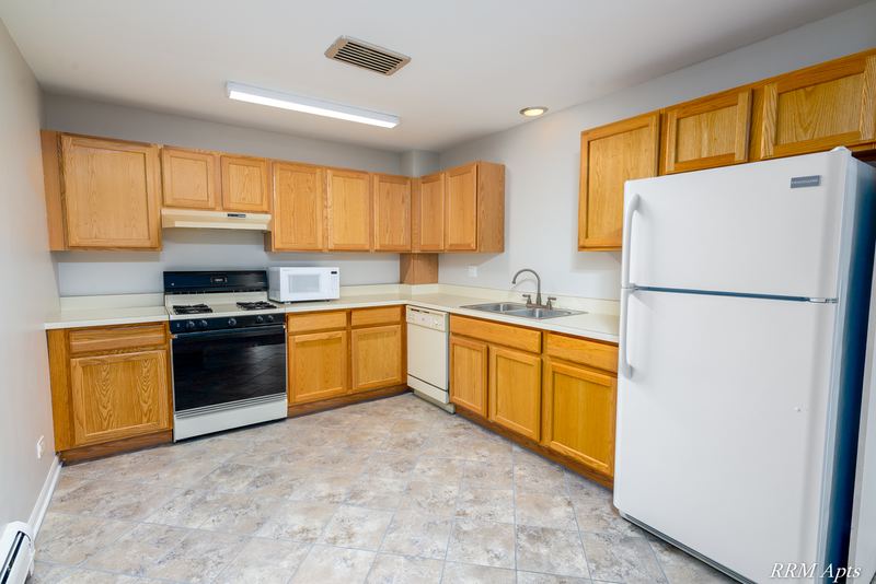 Kitchen with wood cabinets, white refrigerator, white stove, microwave and tile floor, Maple Avenue apartment 2J