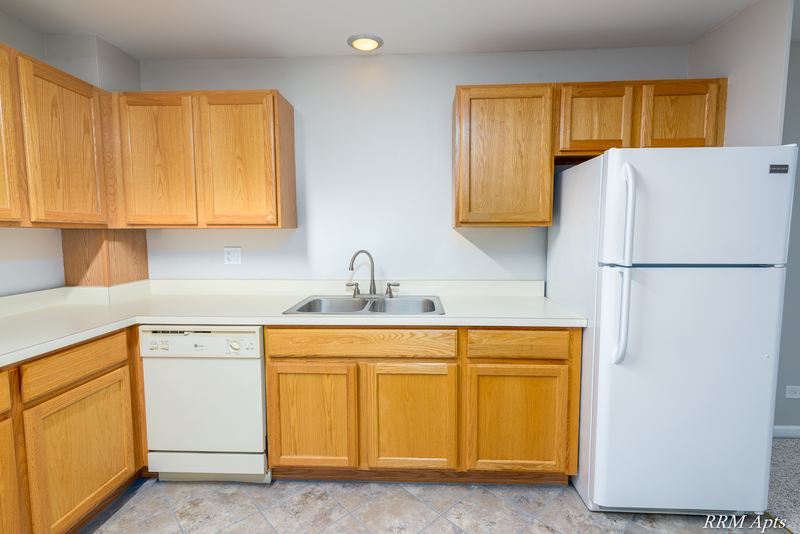 Kitchen with wood cabinets, stainless sink, white dishwasher and white refrigerator, Maple Avenue apartment 2J