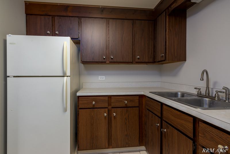Kitchen with dark wood cabinets, white refrigerator and stainless double sink, Maple Avenue apartment LL1