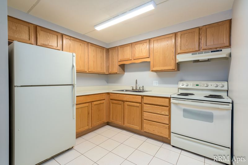 Kitchen with wood cabinets, white refrigerator, white electric stove and tile floor, Maple Avenue apartment LL2