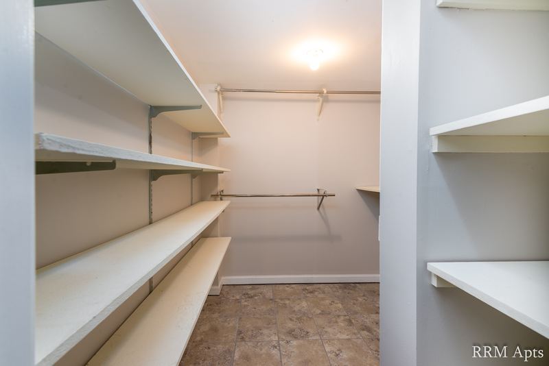 Storage closet with white shelves on three walls and tile floor, Maple Avenue apartment LL2