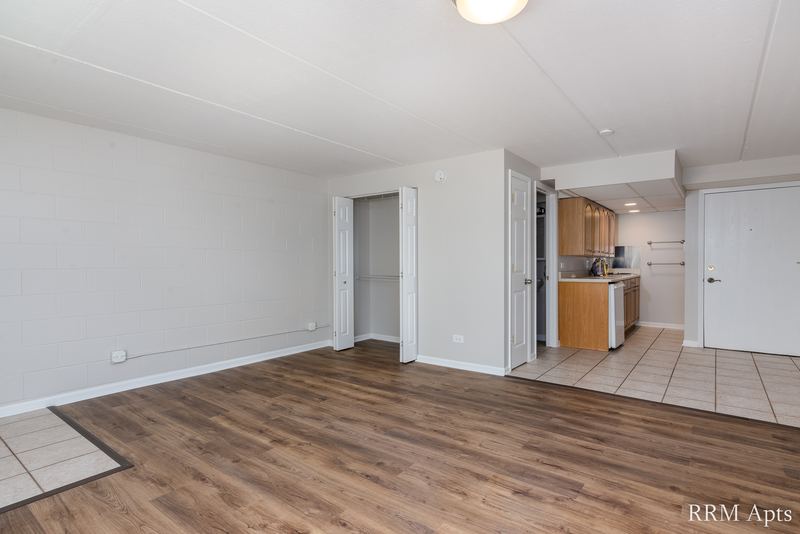 Living room with wood laminate floor and a view through to the kitchen with wood cabinets, Maple Avenue apartment LL4