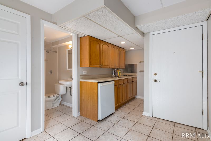 Kitchen with wood cabinets, white dishwasher, tile floor and white entry door, Maple Avenue apartment LL4