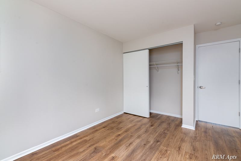Bedroom with open closet and door, wood-look floor, Oriole Court apartment 1A