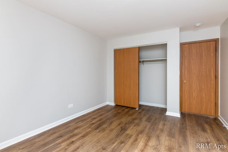 Bedroom with wood laminate floor, an open closet with wood bifold doors and a wood door, Oriole Court apartment 1B