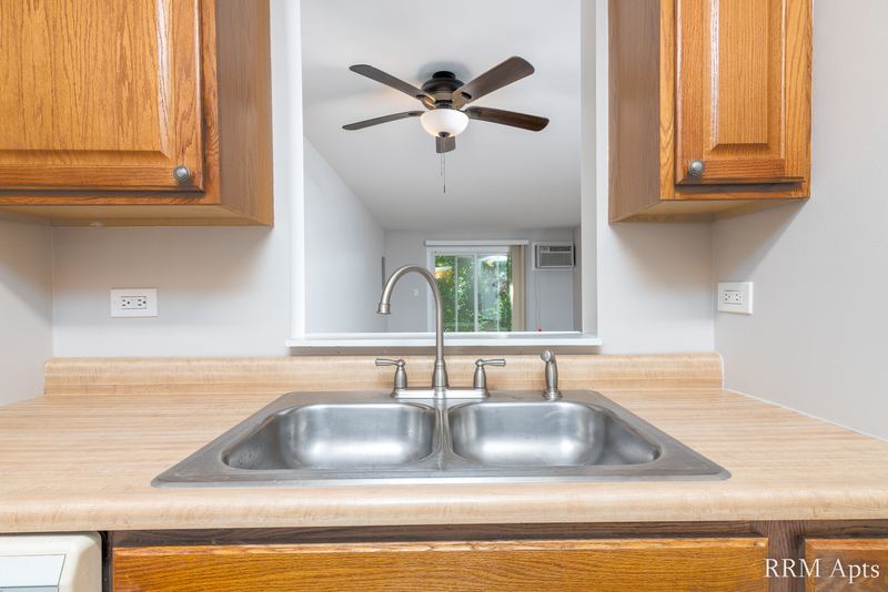 Kitchen with wood cabinets, stainless double sink and a pass-through opening to the living room, Oriole Court apartment 1B