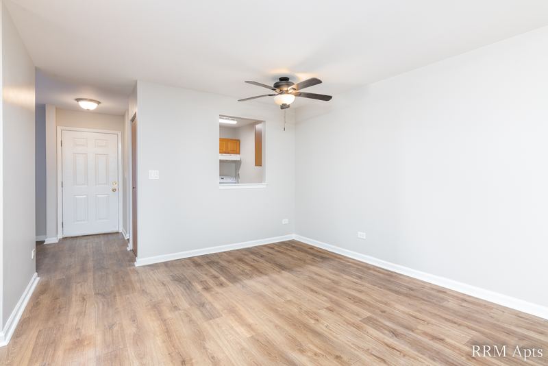 Dining area with wood laminate floor, ceiling fan, white entry door and kitchen pass-through, Oriole Court apartment 1B