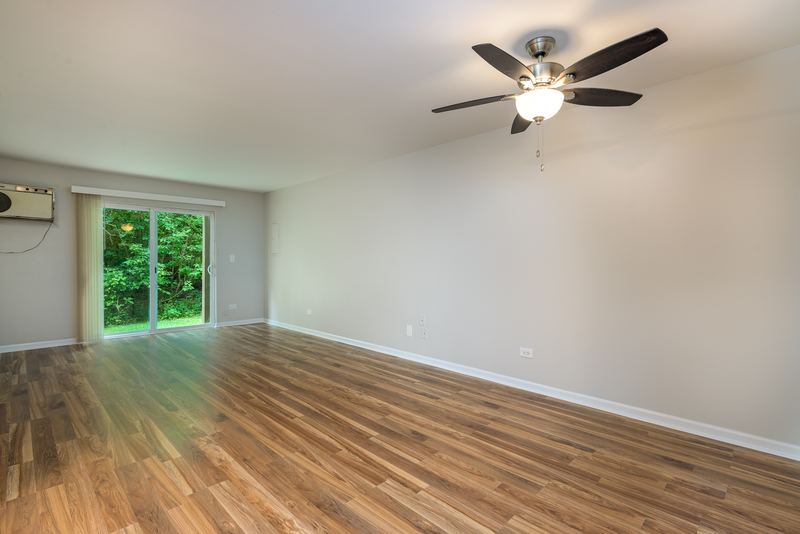 Living room with wood laminate floor, ceiling fan, sliding glass door and wall air conditioner, Oriole Court apartment 1C