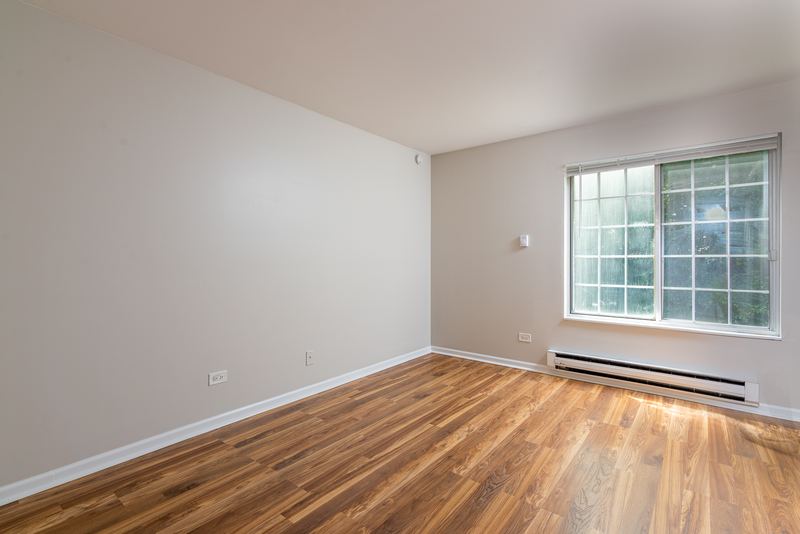 Bedroom with wood laminate floor, a grid-pane window and baseboard heat, Oriole Court apartment 1C
