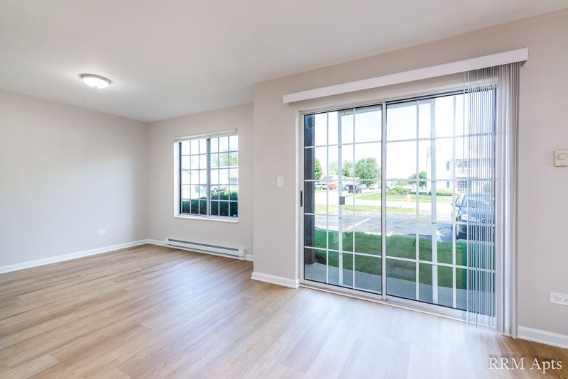 Living room with wood-look floor, window and sliding glass door to the lawn, Oriole Court apartment 1F