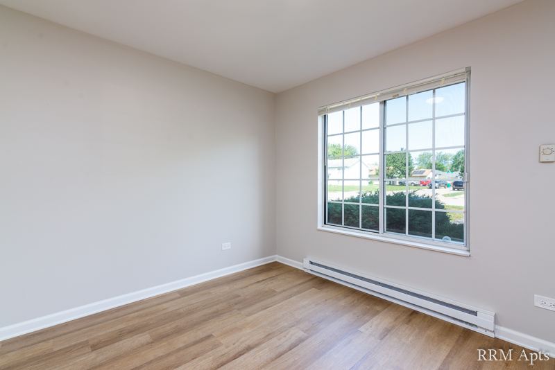 Bedroom with large window, baseboard heater and wood-look floor, Oriole Court apartment 1F