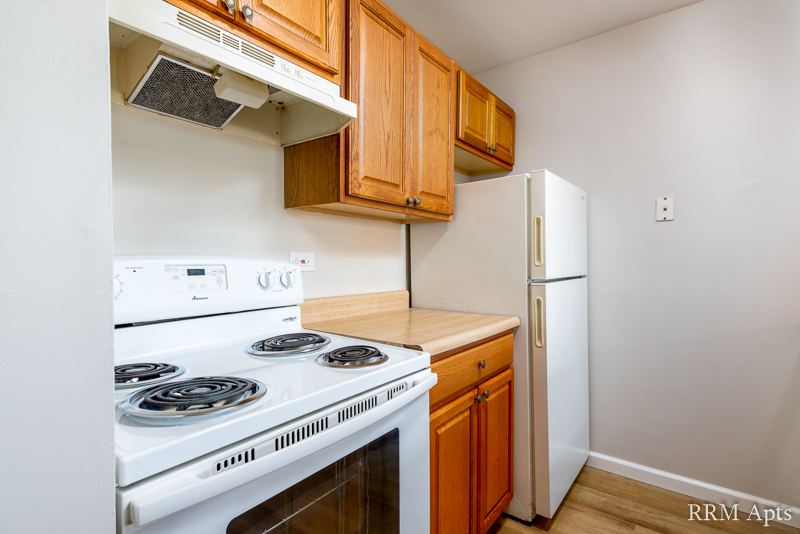 Kitchen with oak cabinets, white electric stove and refrigerator, Oriole Court apartment 1F