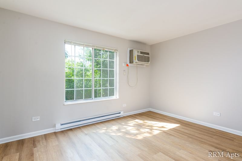 Bedroom with large window, wall air conditioner and wood-look floor, Oriole Court apartment 1F