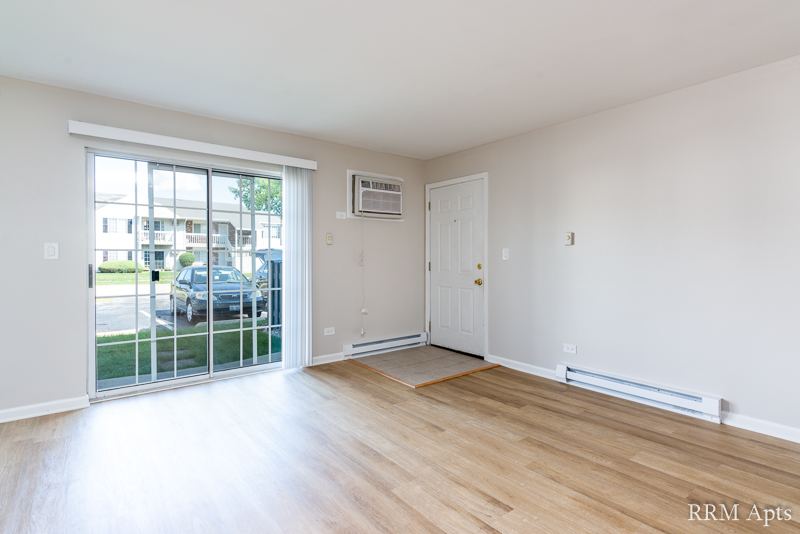 Living room with sliding glass door, wall air conditioner and front door, Oriole Court apartment 1F