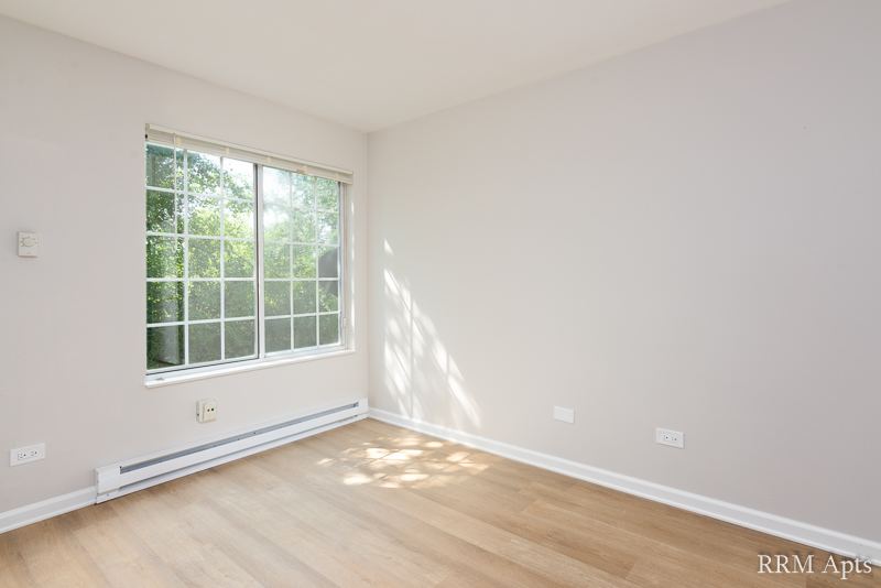 Bedroom with large window, baseboard heater and wood-look floor, Oriole Court apartment 1F