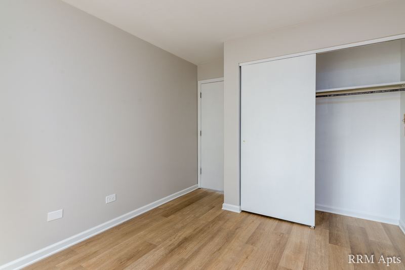 Bedroom with closet with sliding doors and wood-look floor, Oriole Court apartment 1F