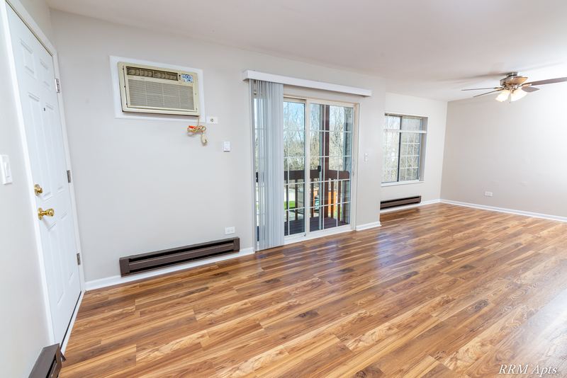Living room with wood laminate floor, wall air conditioner and sliding door to the balcony, Oriole Court apartment 2A
