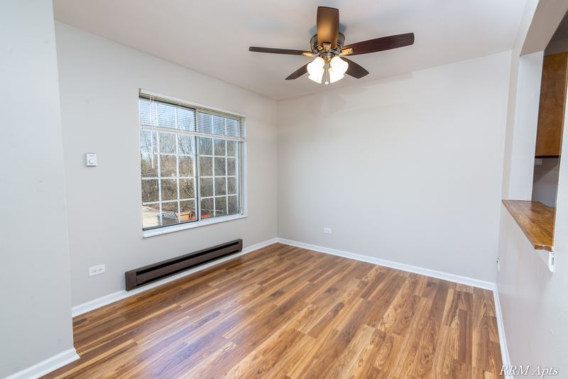 Dining area with wood laminate floor, ceiling fan, a grid-pane window and baseboard heat, Oriole Court apartment 2A