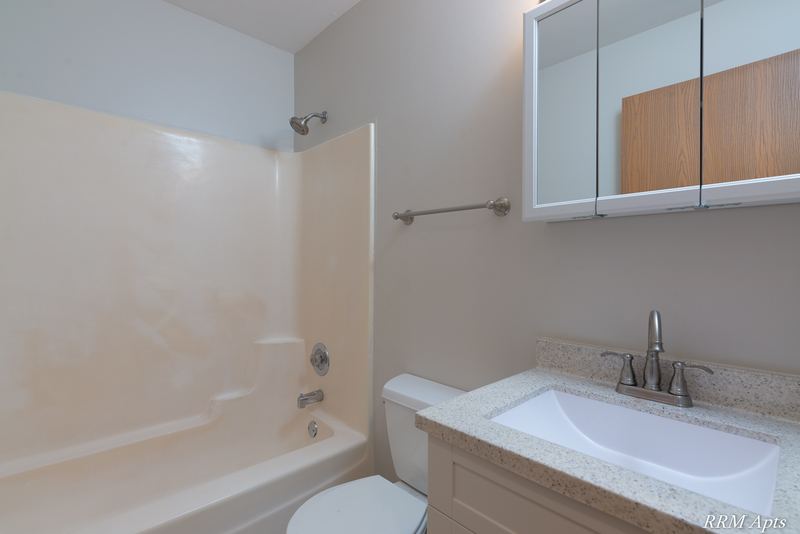 Bathroom with white tub surround, white vanity, mirrored medicine cabinet and toilet, Oriole Court apartment 2B