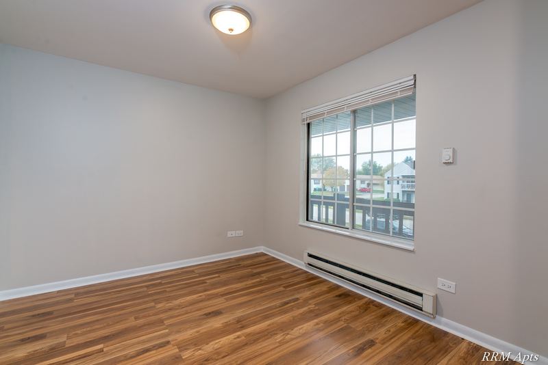 Bedroom with wood laminate floor, a grid-pane window looking out on houses and baseboard heat, Oriole Court apartment 2B