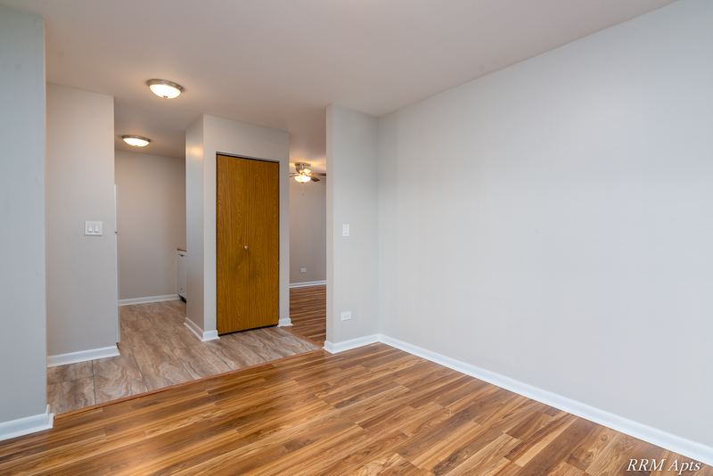 Dining area with wood laminate floor and a hallway with wood doors and ceiling light, Oriole Court apartment 2B