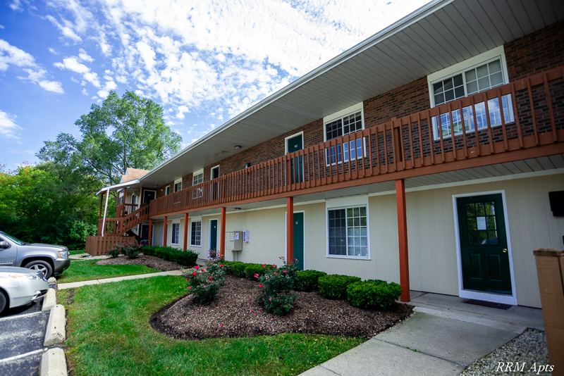 Building exterior with two stories of brick, wood balconies and a landscaped lawn, Oriole Court apartment 2D