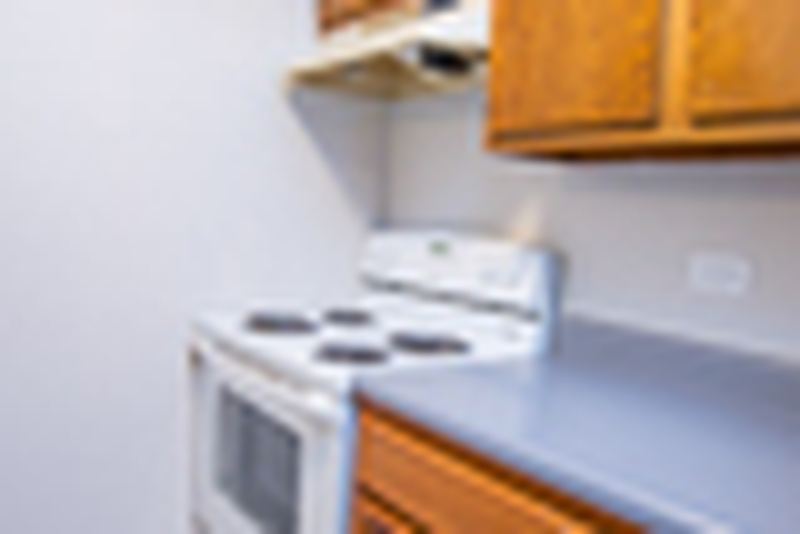 Kitchen with wood cabinets, white electric stove and gray counter, Oriole Court apartment 2D
