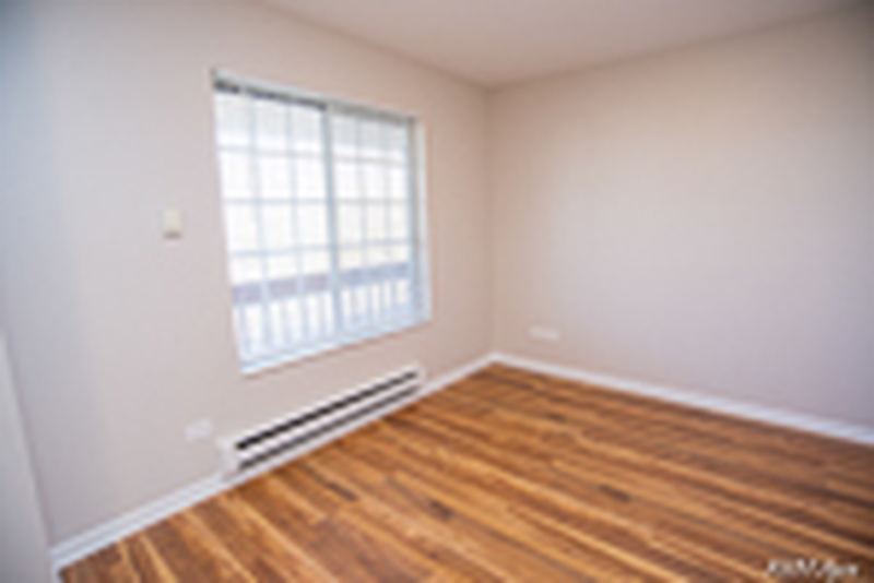 Bedroom with wood laminate floor, a grid-pane window and baseboard heat, Oriole Court apartment 2D