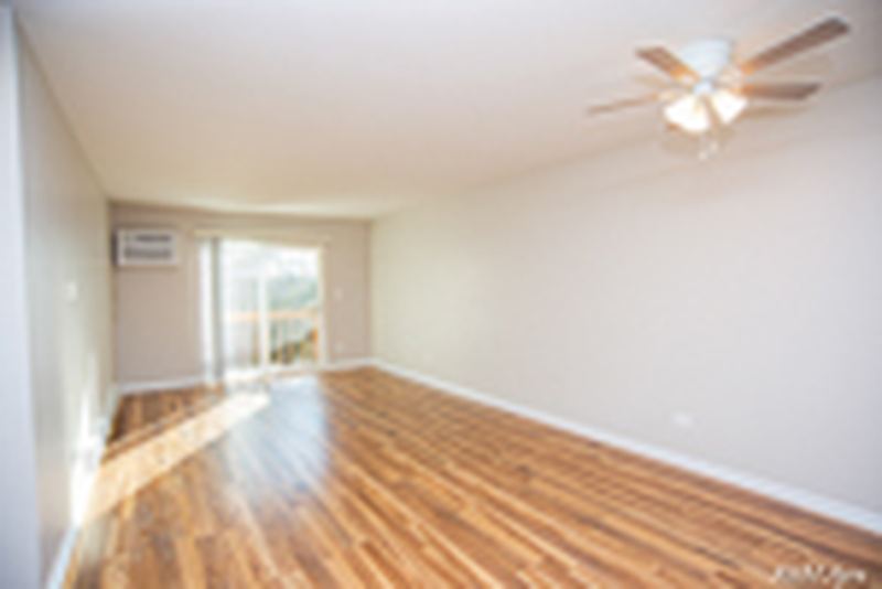 Living room with wood laminate floor, ceiling fan, wall air conditioner and door to the balcony, Oriole Court apartment 2D