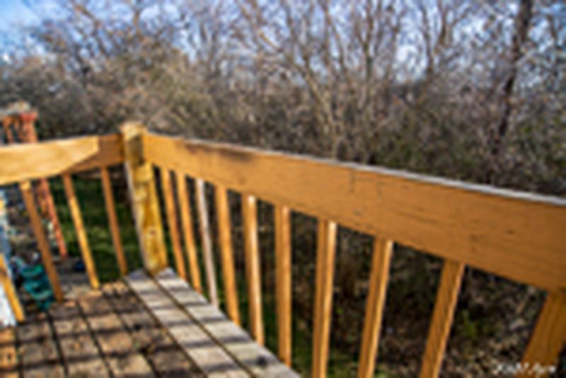 Balcony with wood railing overlooking bare trees and brush, Oriole Court apartment 2D