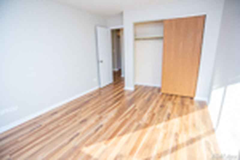 Bedroom with wood laminate floor, an open closet with wood bifold door and a doorway, Oriole Court apartment 2D