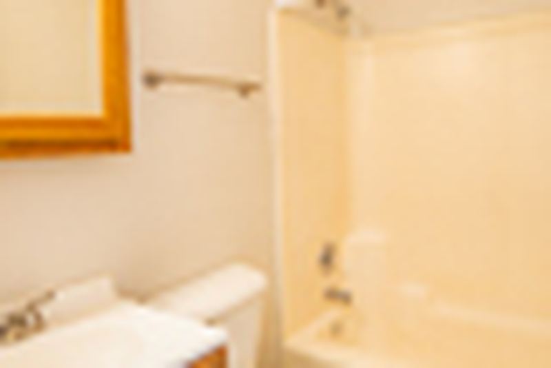 Bathroom with white tub surround, mirrored medicine cabinet, towel bar and toilet, Oriole Court apartment 2D