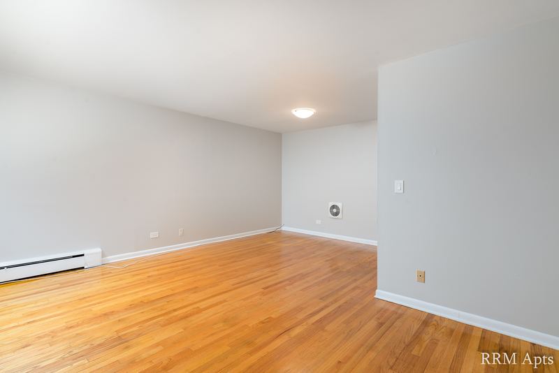 Living room with wood floor, gray walls, baseboard heater and an opening to the next room, Park Avenue apartment 603 103