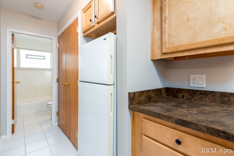 Kitchen with white refrigerator, oak cabinets, tile floor and a doorway to the bathroom, Park Avenue apartment 603 103