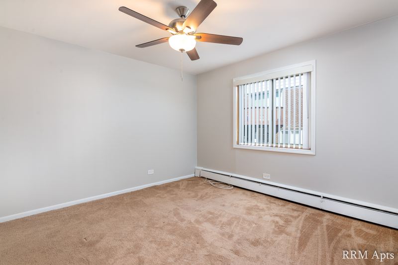 Bedroom with beige carpet, ceiling fan, window with vertical blinds and a baseboard heater, Park Avenue apartment 603 103