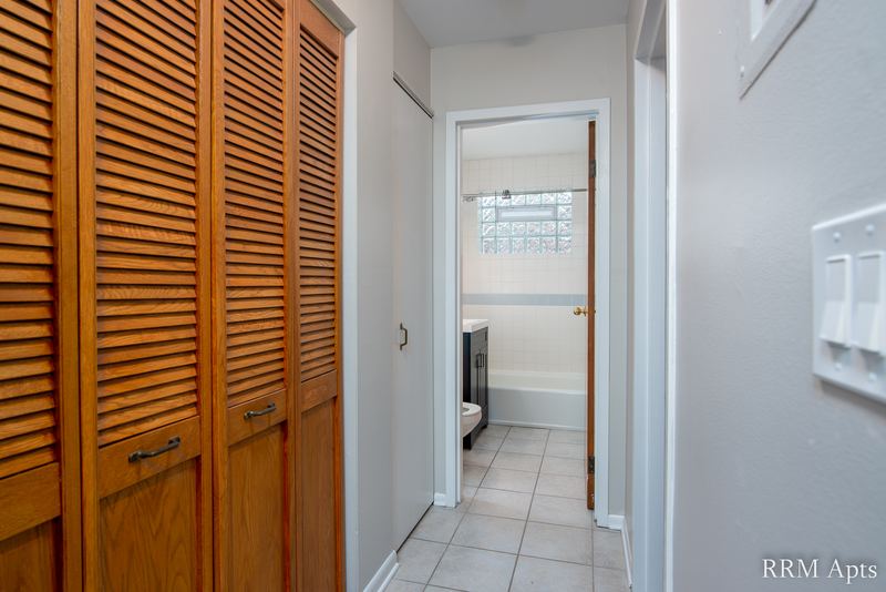 Hallway with louvered oak closet doors, tile floor and a view into the bathroom, Park Avenue apartment 603 104
