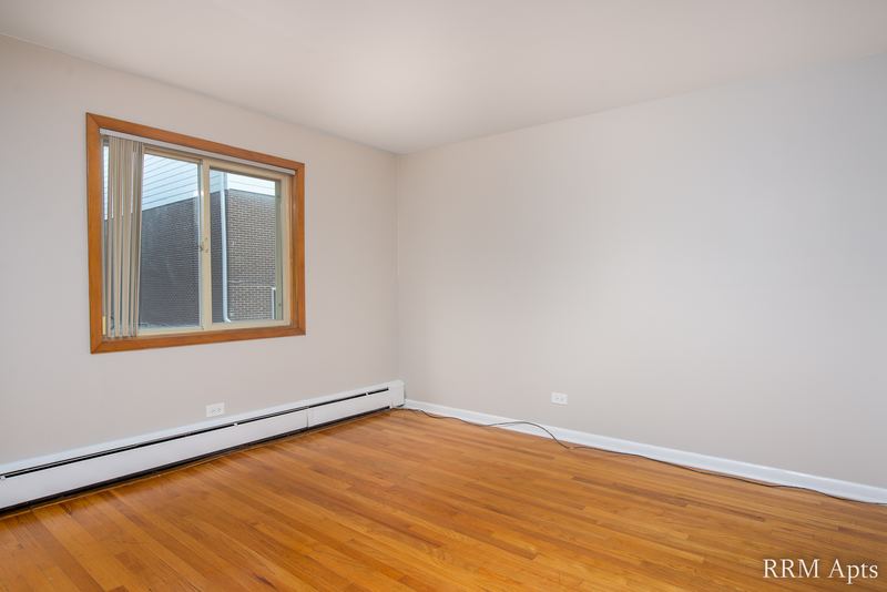 Bedroom with wood floor, gray walls, oak-trimmed window and a baseboard heater, Park Avenue apartment 603 104