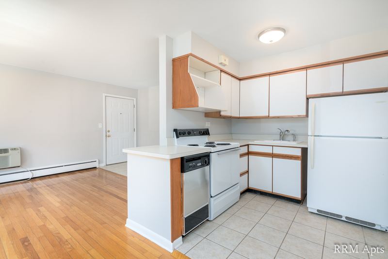 Kitchen with white oak-trimmed cabinets, white stove, refrigerator and tile floor, Park Avenue apartment 603 106