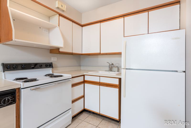 Kitchen with white oak-trimmed cabinets, white stove, refrigerator and a black dishwasher, Park Avenue apartment 603 106