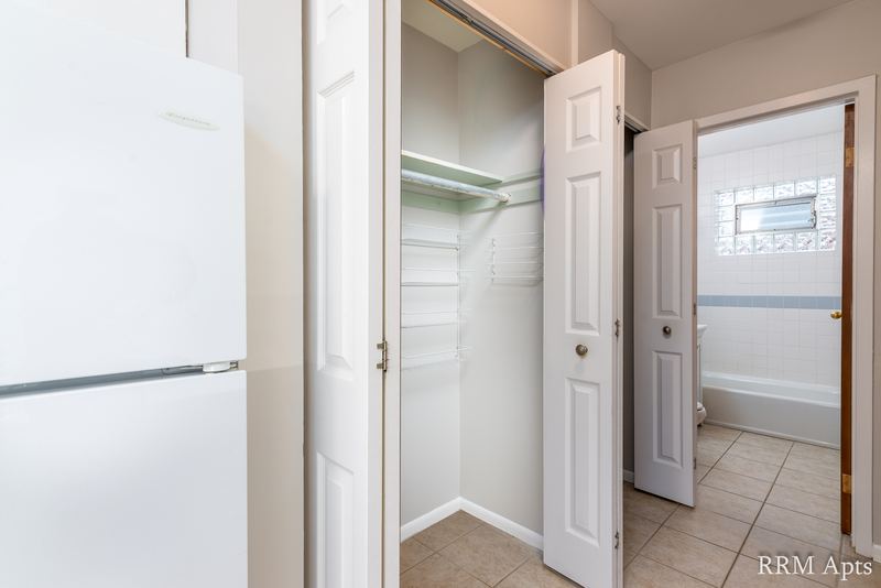 Hallway with white refrigerator, open closet, tile floor and a view into the bathroom, Park Avenue apartment 603 106