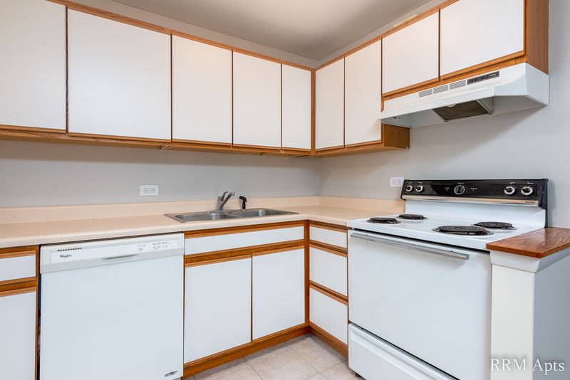 Kitchen with white oak-trimmed cabinets, white dishwasher, electric stove and tile floor, Park Avenue apartment 603 205
