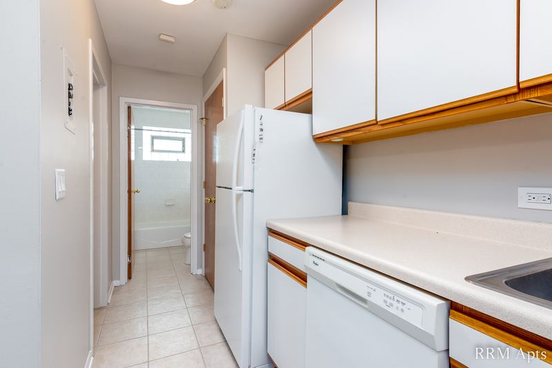 Kitchen with white cabinets, white refrigerator, dishwasher and a hallway to the bathroom, Park Avenue apartment 603 205
