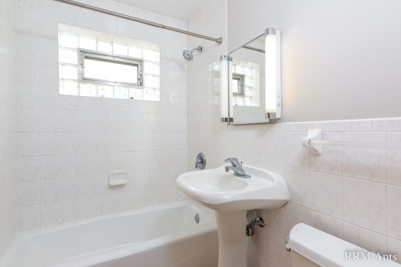 Bathroom with white tile walls, glass block window, pedestal sink and a mirrored cabinet, Park Avenue apartment 603 205