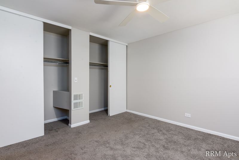 Bedroom with gray carpet, ceiling fan and two open closets with shelves, Park Avenue apartment 603 205